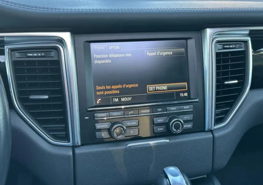Vue rapprochée de la console centrale du Porsche Macan gris foncé, affichage multimédia et commandes intégrées.