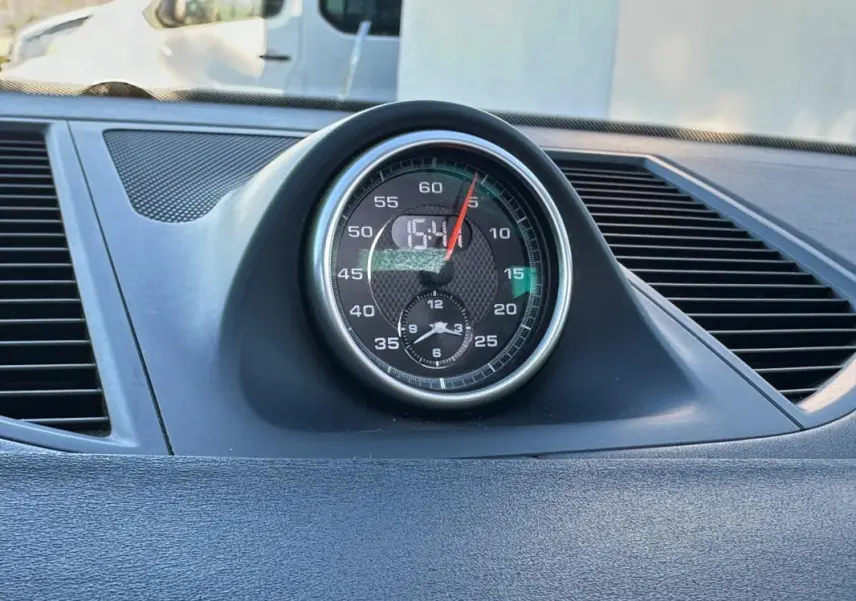 Gros plan sur l'horloge centrale du tableau de bord du Porsche Macan gris foncé de 2015.