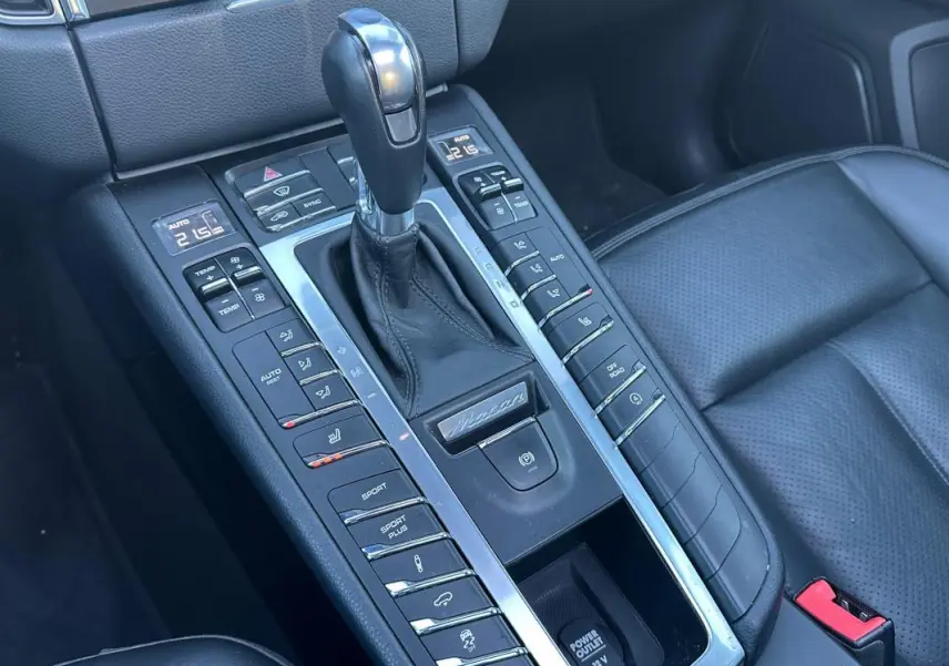 Vue rapprochée de la console centrale cuir noire du Porsche Macan 2015 avec levier de vitesse et commandes multiples.