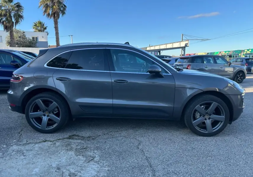 Vue de profil côté gauche d'un Porsche Macan gris foncé 2015 avec jantes 18 pouces et vitres teintées.