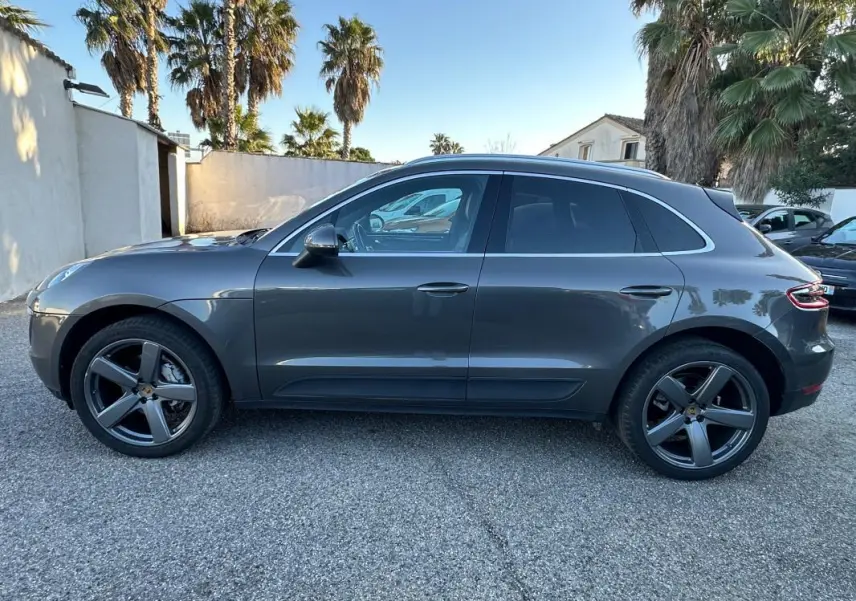 Vue latérale droite d'un Porsche Macan gris foncé avec jantes 18 pouces et vitres teintées, stationné en extérieur.