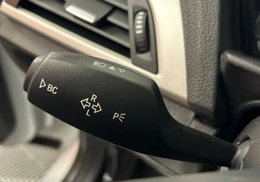 Le levier de clignotant noir avec commandes BC et feux sur le tableau de bord intérieur d'une BMW Série 1 gris diesel.