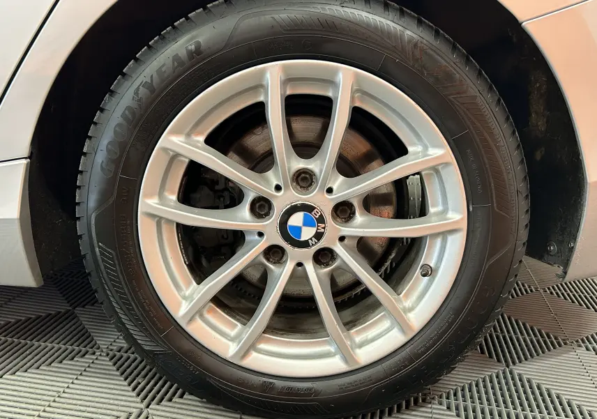 Gros plan sur la jante alliage argentée et pneu Goodyear d'une BMW Série 1 gris 2014 côté avant droit.