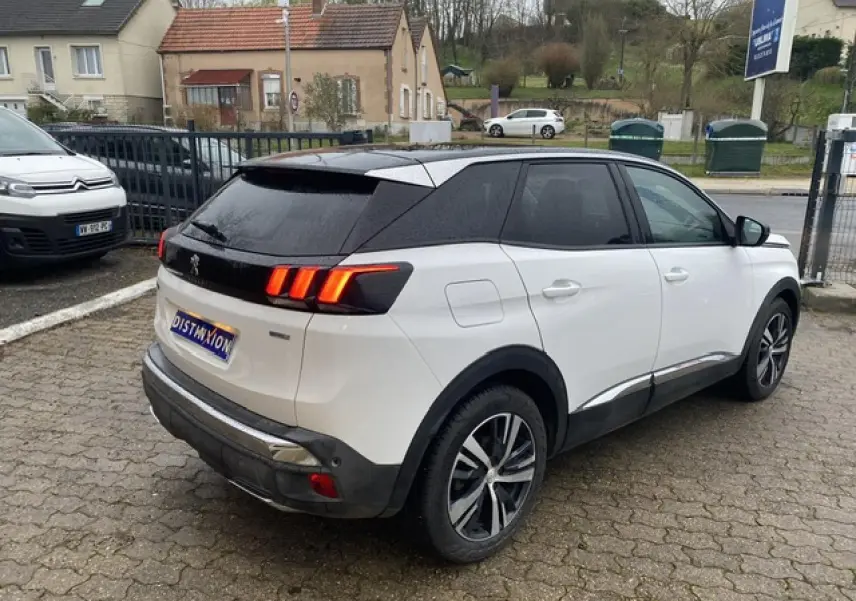 Peugeot 3008 blanc avec toit noir en vue 3/4 arrière côté droit, jantes alliage bi-ton et feux arrière allumés.