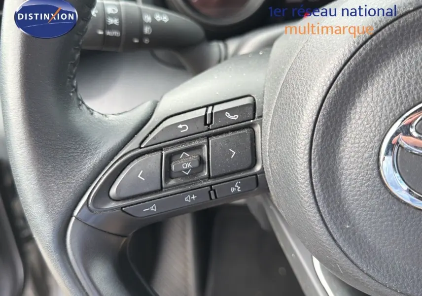 Gros plan sur les commandes au volant noir d'une Toyota Yaris Cross 116h Design AWD-i 2023.