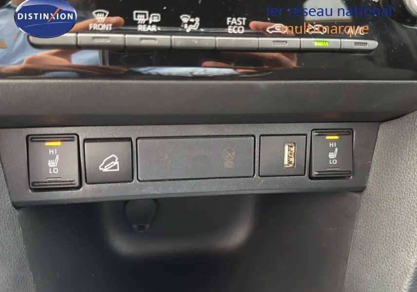 Vue rapprochée des commandes de sièges chauffants et prises USB sur la console centrale d'une Toyota Yaris Cross gris minéral.