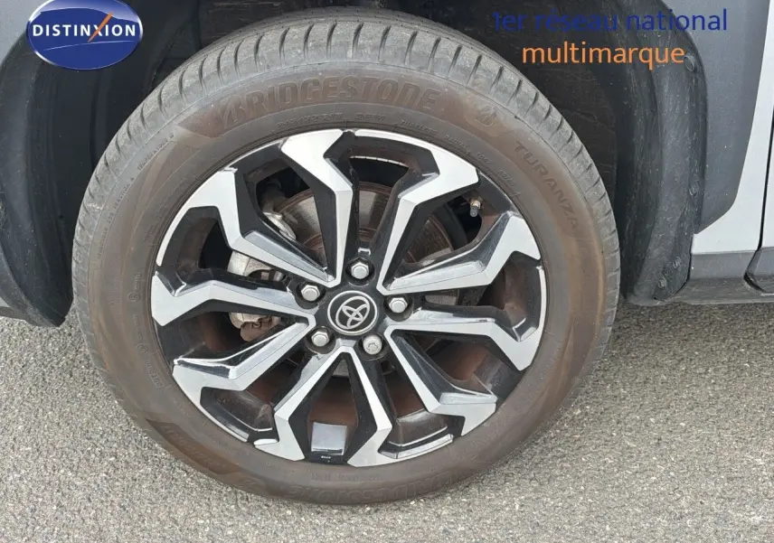 Gros plan sur la roue avant droite de la Toyota Yaris Cross gris minéral avec jante alliage noire et argentée.