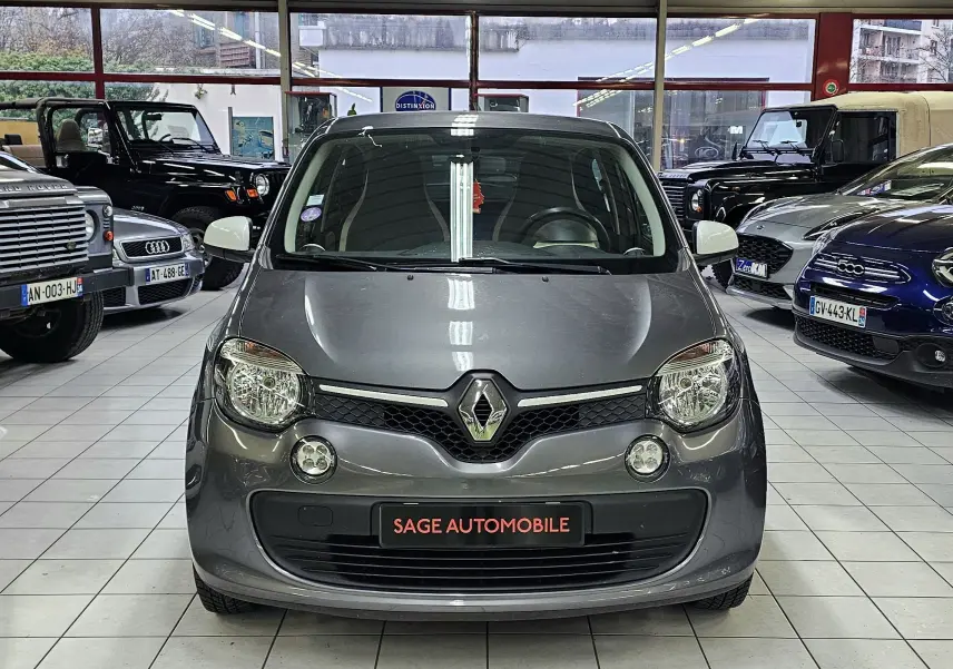 Vue avant d'une Renault Twingo III gris lunaire 2018, exposée en showroom avec logo Renault bien visible.