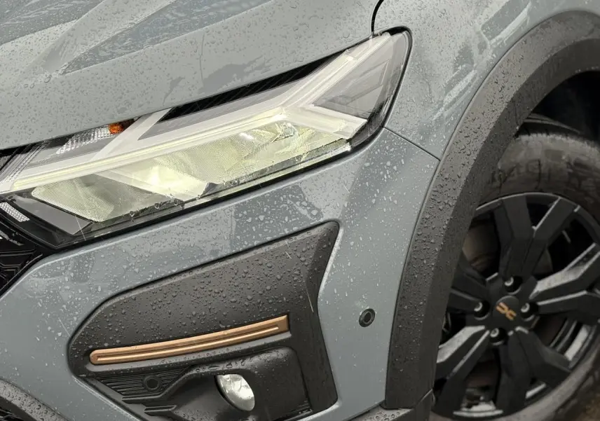 Gros plan sur l'avant droit gris urbain du Dacia Jogger 1.6 Hybrid 140 avec feux LED et jante noire Mahalia.