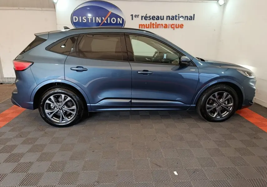 Vue de profil droit d'un Ford Kuga 2024 bleu métallisé, finition St Line avec jantes alliage et vitres teintées.