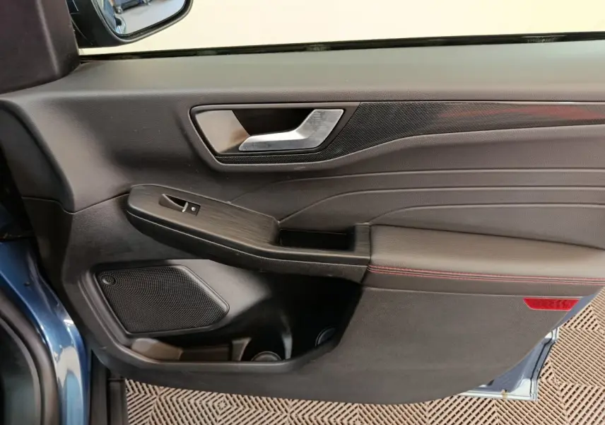 Vue intérieure du panneau de porte avant gauche bleu du Ford Kuga 2024, finition St Line avec surpiqûres rouges.