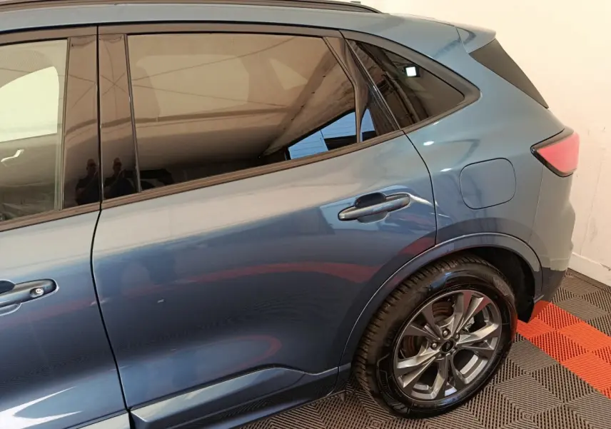 Vue latérale arrière droite du Ford Kuga 2024 bleu métallisé, mettant en valeur la roue alliage et les vitres teintées.