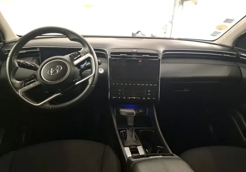 Vue intérieure du tableau de bord noir du Hyundai Tucson 2021 avec volant multifonction et écran tactile central.