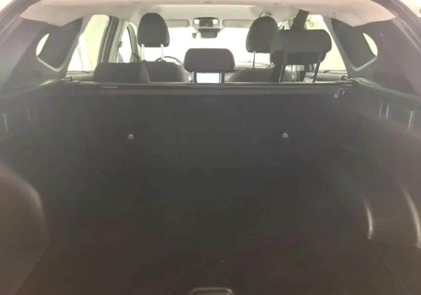 Vue intérieure du coffre du Hyundai Tucson blanc 2021, montrant l'espace de chargement et les sièges arrière.