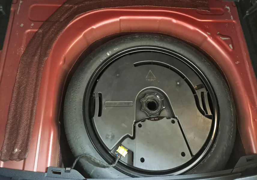 Gros plan sur la roue de secours noire intégrée dans le coffre rouge Roi du Volkswagen Taigo 2021.
