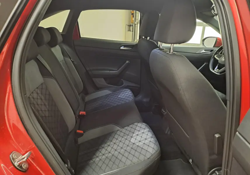 Vue intérieure côté gauche des sièges arrière du Volkswagen Taigo Rouge Roi, montrant les tissus noirs à motifs géométriques.