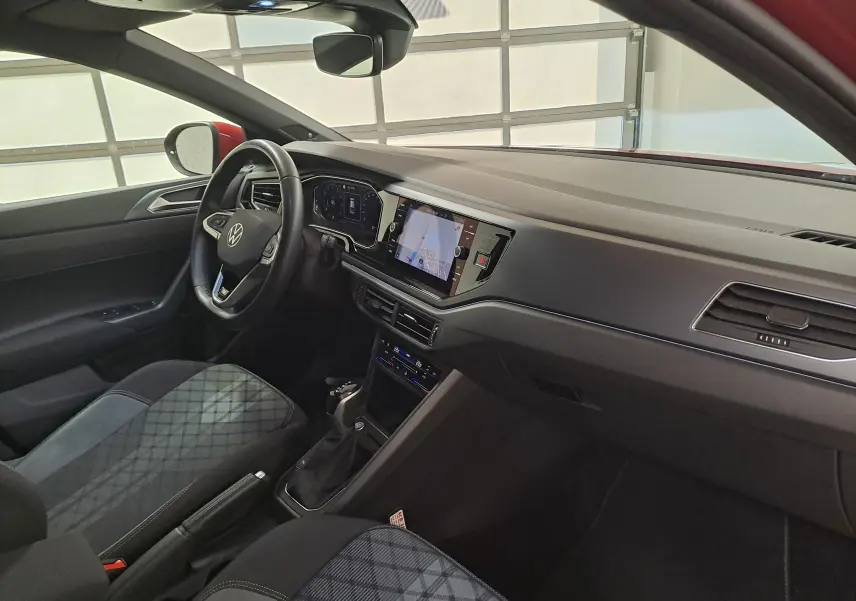 Vue intérieure côté conducteur du Volkswagen Taigo 1.5 TSI 150 DSG7 R-Line avec tableau de bord moderne et sièges tissu à motifs.