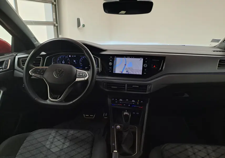 Vue intérieure avant du Volkswagen Taigo 1.5 TSI R-Line 2021, tableau de bord noir avec écran tactile et volant multifonction.
