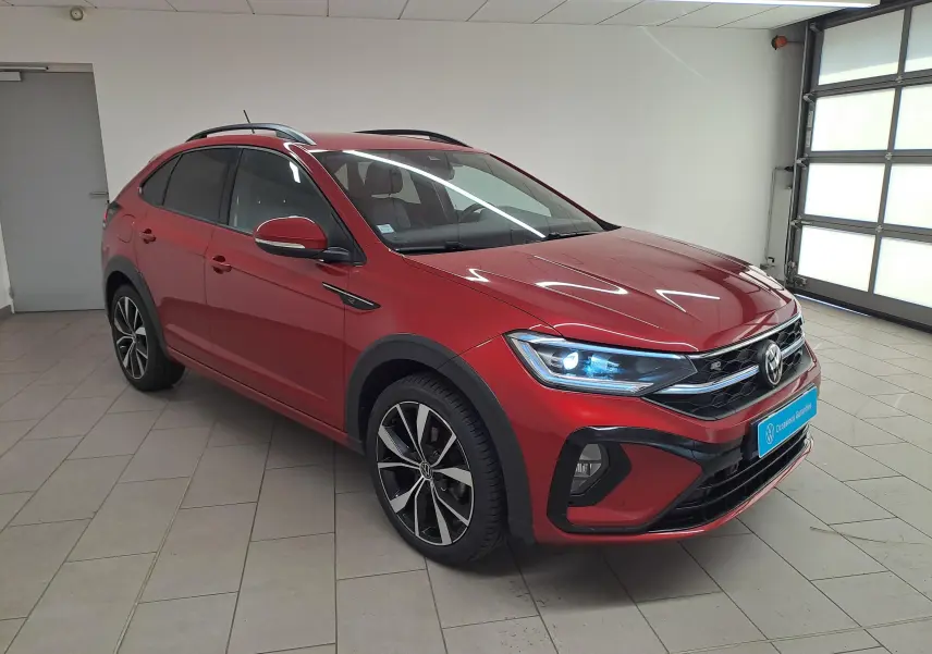 Volkswagen Taigo 1.5 TSI R-Line rouge Roi en 3/4 avant droit, jantes noires brillantes et phares allumés.