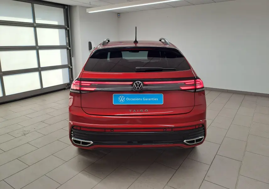 Vue arrière d'un Volkswagen Taigo 1.5 TSI 150 DSG7 R-LINE rouge Roi avec feux LED allumés dans un garage.