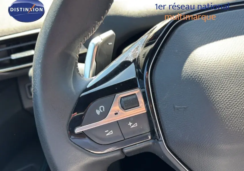 Gros plan sur les commandes gauche du volant cuir du Peugeot 3008 Hybrid 2024, soulignant les boutons multifonctions.