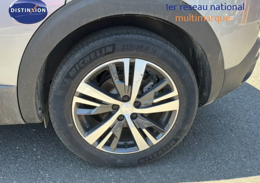 Gros plan sur la roue avant gauche du Peugeot 3008 gris Artense métal avec jante alliage bicolore et pneu Michelin.