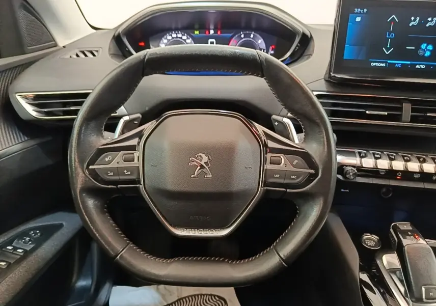 Vue intérieure centrée sur le volant cuir multifonctions d'une Peugeot 3008 2022 avec tableau de bord digital et écran tactile.