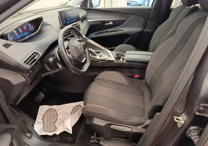 Vue intérieure côté conducteur du Peugeot 3008 gris foncé, volant cuir multifonctions et tableau de bord digital.