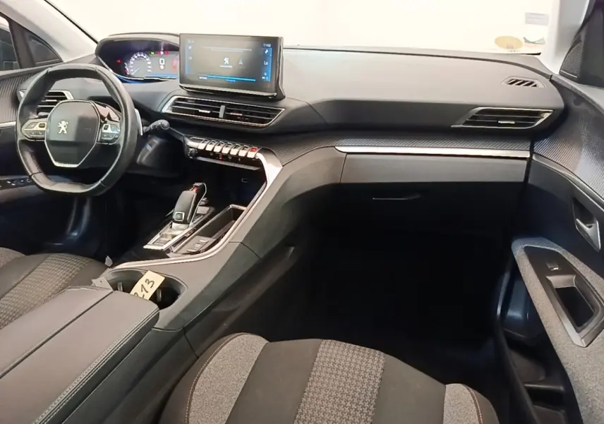 Vue intérieure côté conducteur du Peugeot 3008 gris foncé 2022, avec volant cuir multifonctions et écran tactile central.
