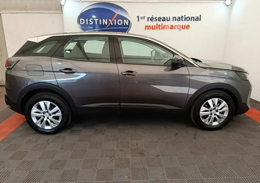 Profil côté droit d’un Peugeot 3008 gris foncé 2022 garé en intérieur avec jantes alliage et toit blanc.