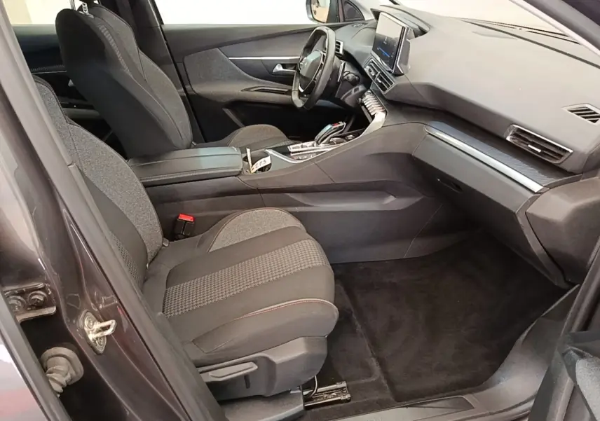 Vue intérieure côté passager avant du Peugeot 3008 gris foncé, montrant sièges tissu et tableau de bord moderne.