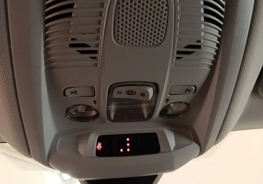 Vue en gros plan du plafonnier gris clair avec commandes d’éclairage et indicateur de ceinture allumée dans un Peugeot 3008 gris foncé.
