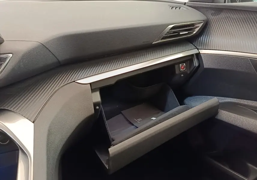 Intérieur du Peugeot 3008 2022, vue côté passager sur la boîte à gants ouverte avec tableau de bord gris foncé.