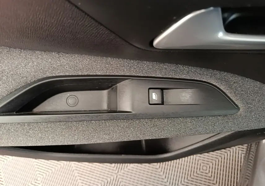 Détail de la commande de verrouillage de porte sur la garniture intérieure côté conducteur d’un Peugeot 3008 gris foncé.