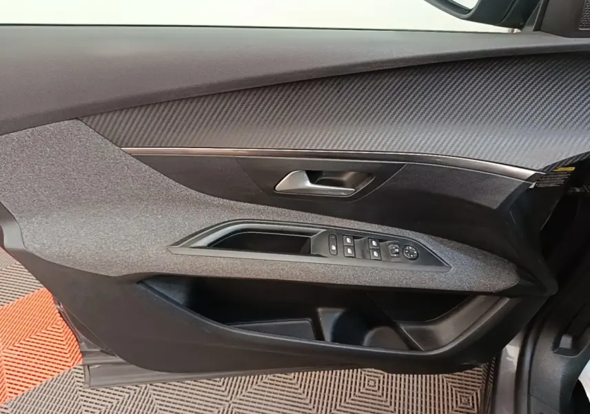 Vue rapprochée de la porte avant gauche du Peugeot 3008 2022, avec commandes électriques et finition tissu gris foncé.