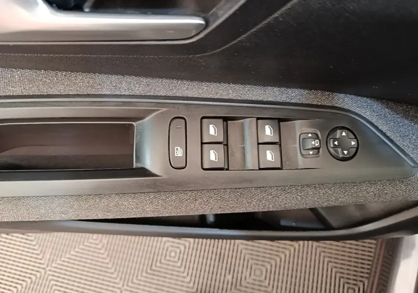 Gros plan sur la commande des vitres électriques côté conducteur d’un Peugeot 3008 gris foncé, avec tissu noir et boutons noirs.
