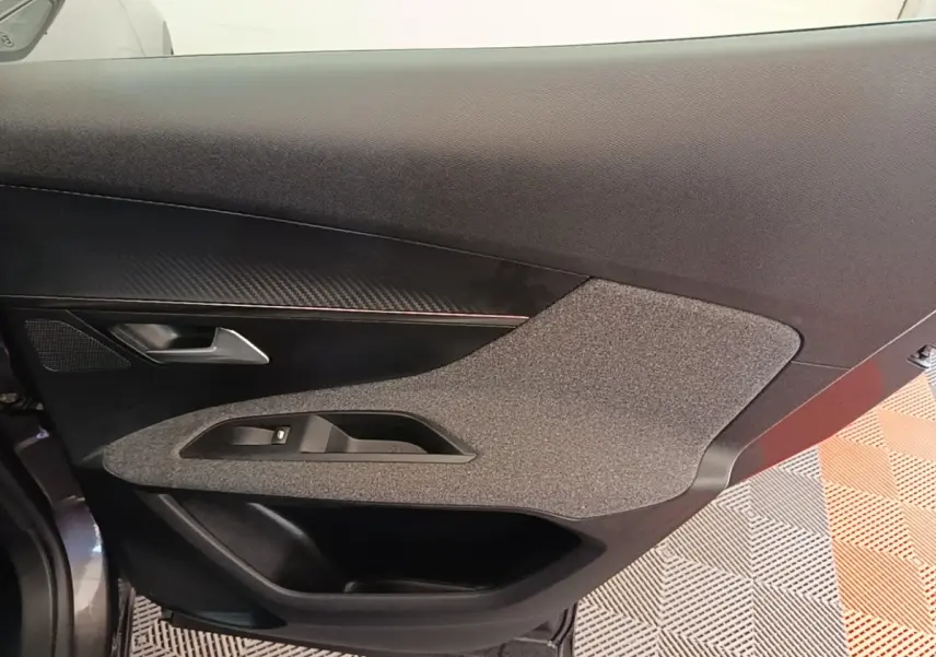 Vue rapprochée de la porte intérieure côté gauche du Peugeot 3008 gris foncé, avec habillage tissu et plastique.