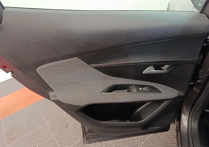 Vue intérieure côté gauche de la porte avant d’un Peugeot 3008 gris foncé, avec habillage tissu et plastique noir.