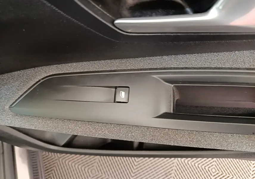 Gros plan sur la commande de lève-vitre côté conducteur du Peugeot 3008 gris foncé, intérieur tissu et plastique.