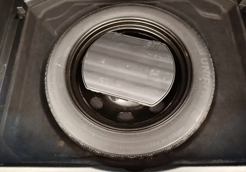 Vue plongeante sur la roue de secours noire dans le coffre d’un Peugeot 3008 gris foncé.