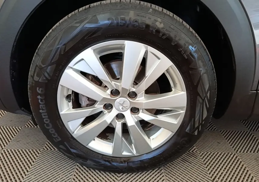 Gros plan sur la roue avant droite du Peugeot 3008 gris foncé avec jante alliage et logo Peugeot central.