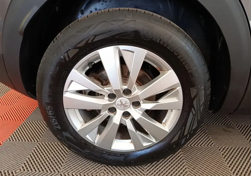 Gros plan sur la roue avant droite avec jante alliage argentée du Peugeot 3008 gris foncé 2022.