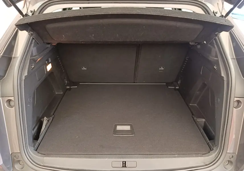 Coffre ouvert d’un Peugeot 3008 gris foncé vu de l’arrière, montrant un espace de chargement propre et spacieux.