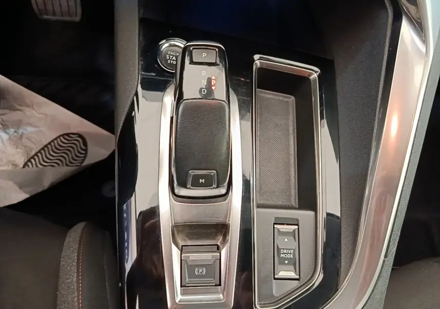 Vue rapprochée de la console centrale noire brillante du Peugeot 3008 2022 avec levier de boîte auto et bouton Drive Mode.