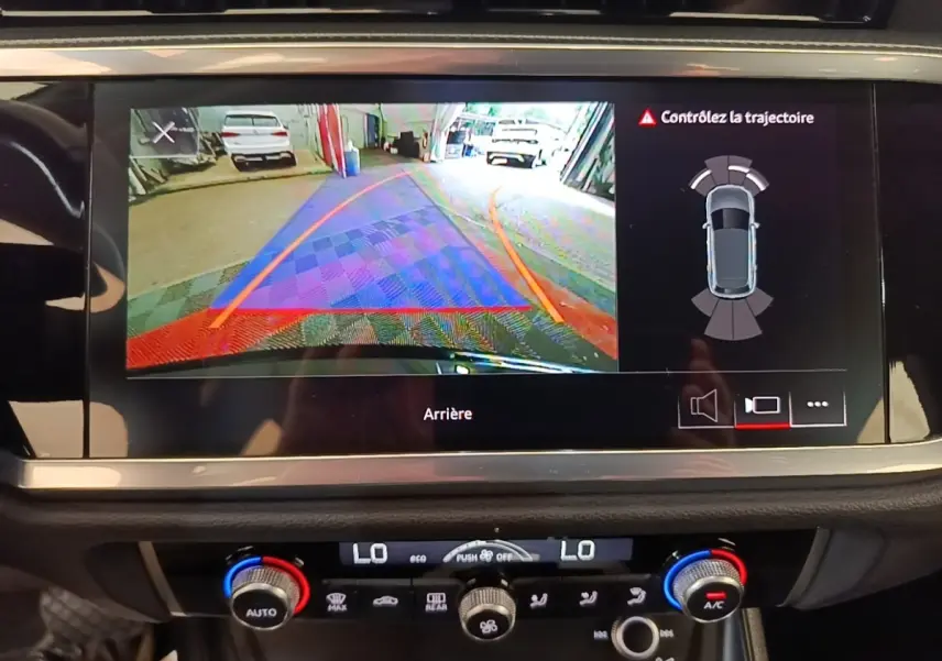 Écran tactile intérieur montrant la caméra de recul et l’aide au stationnement d’un Audi Q3 hybride rechargeable 2023.