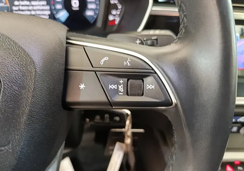 Gros plan sur le volant cuir multifonctions noir de l'Audi Q3 45 TFSI e avec commandes audio et téléphone.