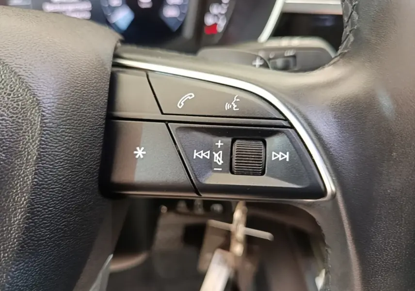 Gros plan sur le côté droit du volant cuir noir d’Audi Q3 45 TFSI e avec commandes audio et vocales.