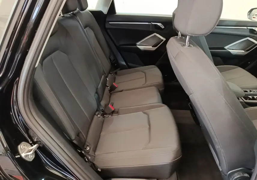 Vue intérieure côté gauche montrant la banquette arrière grise et les sièges avant du SUV Audi Q3 hybride 2023.