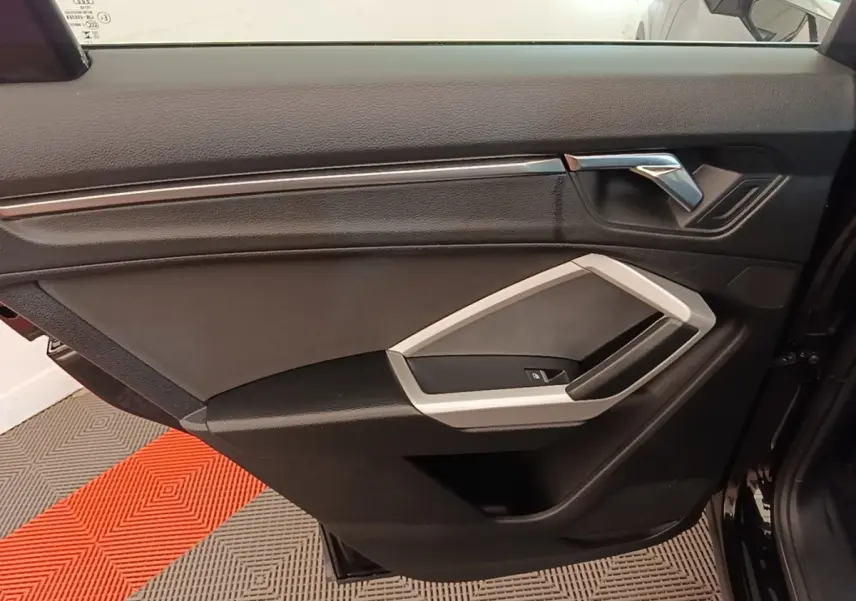 Vue intérieure de la porte côté gauche d’un Audi Q3 45 TFSI e 2023, avec garniture noire et insert argenté.