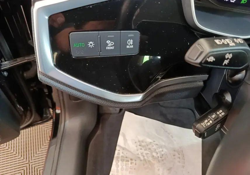 Détail du tableau de bord noir brillant côté gauche avec commandes d’éclairage sur Audi Q3 hybride 2023.
